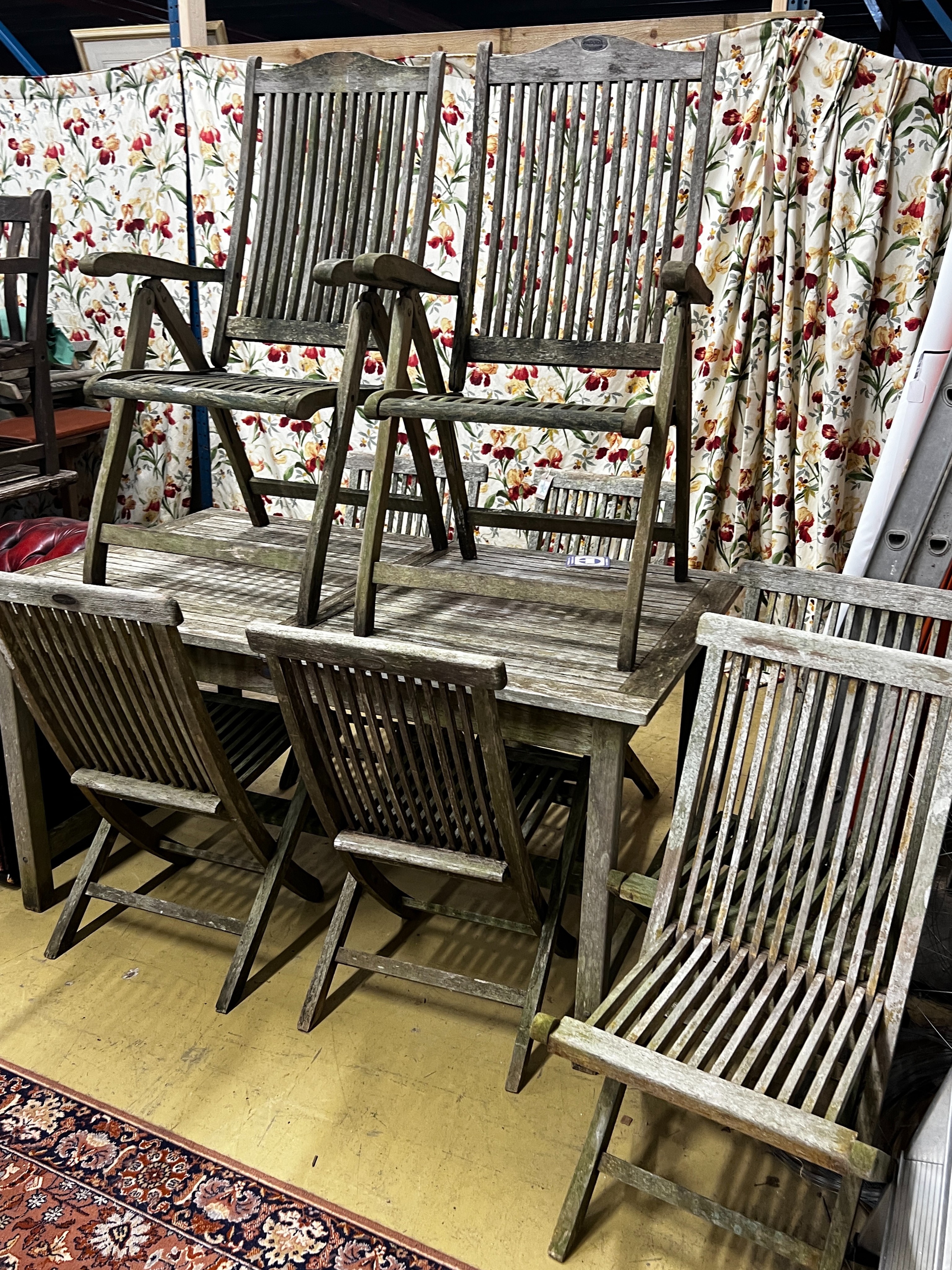 A rectangular weathered teak extending garden table, length 192cm extended, width 89cm, height 76cm together with eight teak folding garden chairs, two with arms